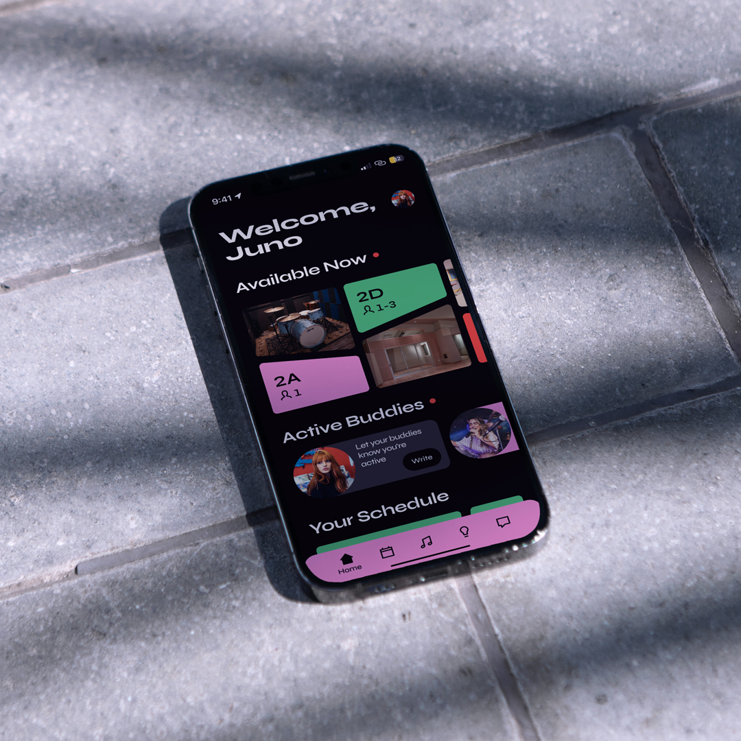 A phone on sunny gray tiles displays BPM’s home screen. Visible features include a welcome message, currently available rooms, and an active buddies message option.
