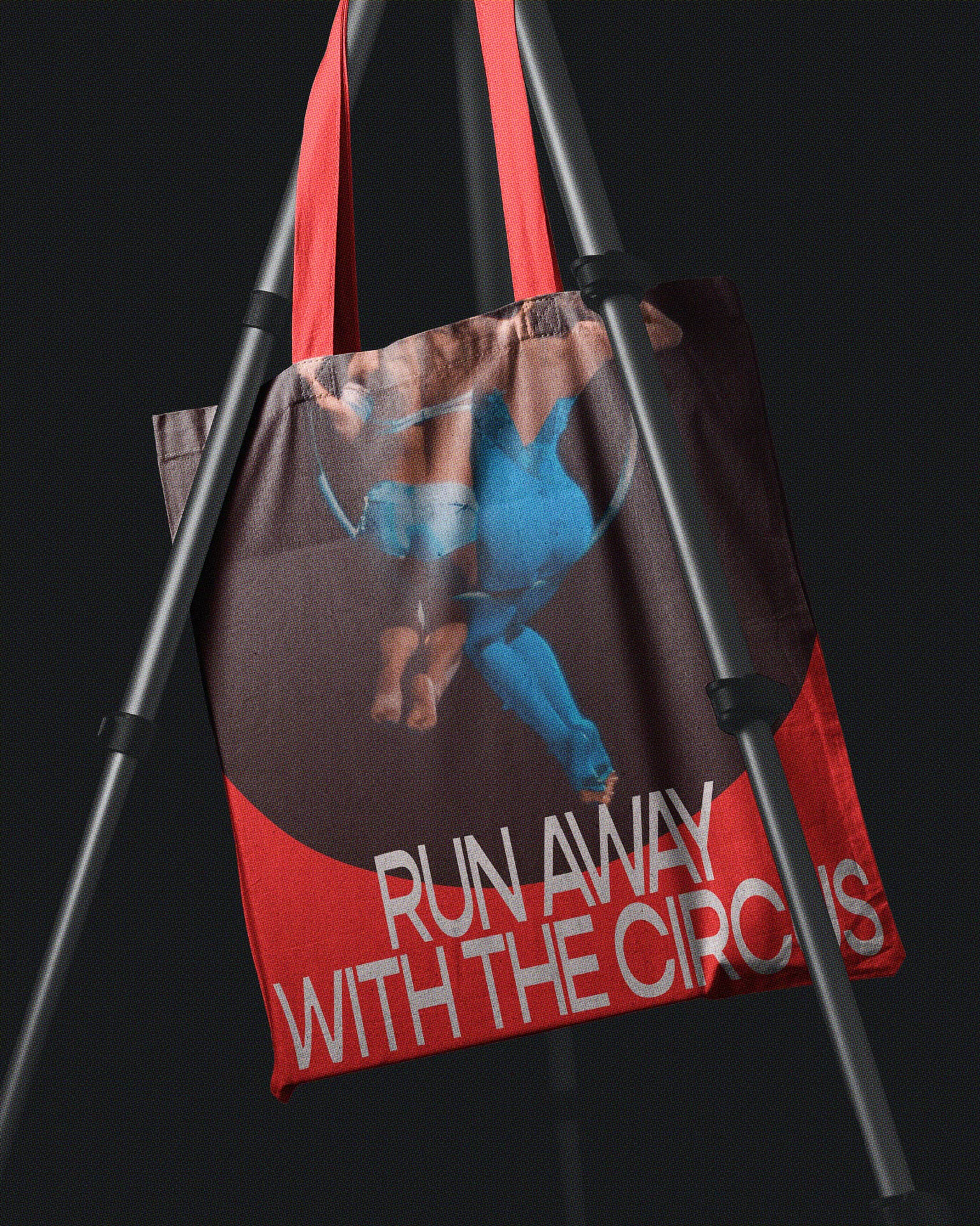 A hanging tote bag with acrobats in an aerial hoop and a “run away with the circus” headline.